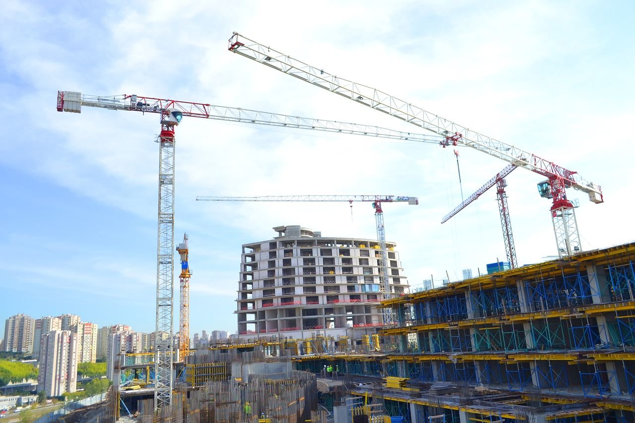 Urban construction site featuring multiple tower cranes against a city skyline.